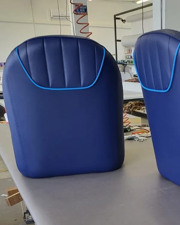 Come lavoriamo: sedile in similpelle blu sul banco del laboratorio, con i rotoli di tessuto sullo sfondo