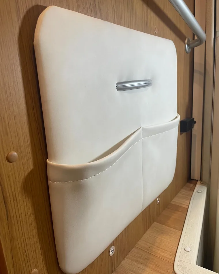 Rifacimento degli interni del camper: pannello imbottito in finta pelle bianca con maniglia cromata e doppia tasca cucita