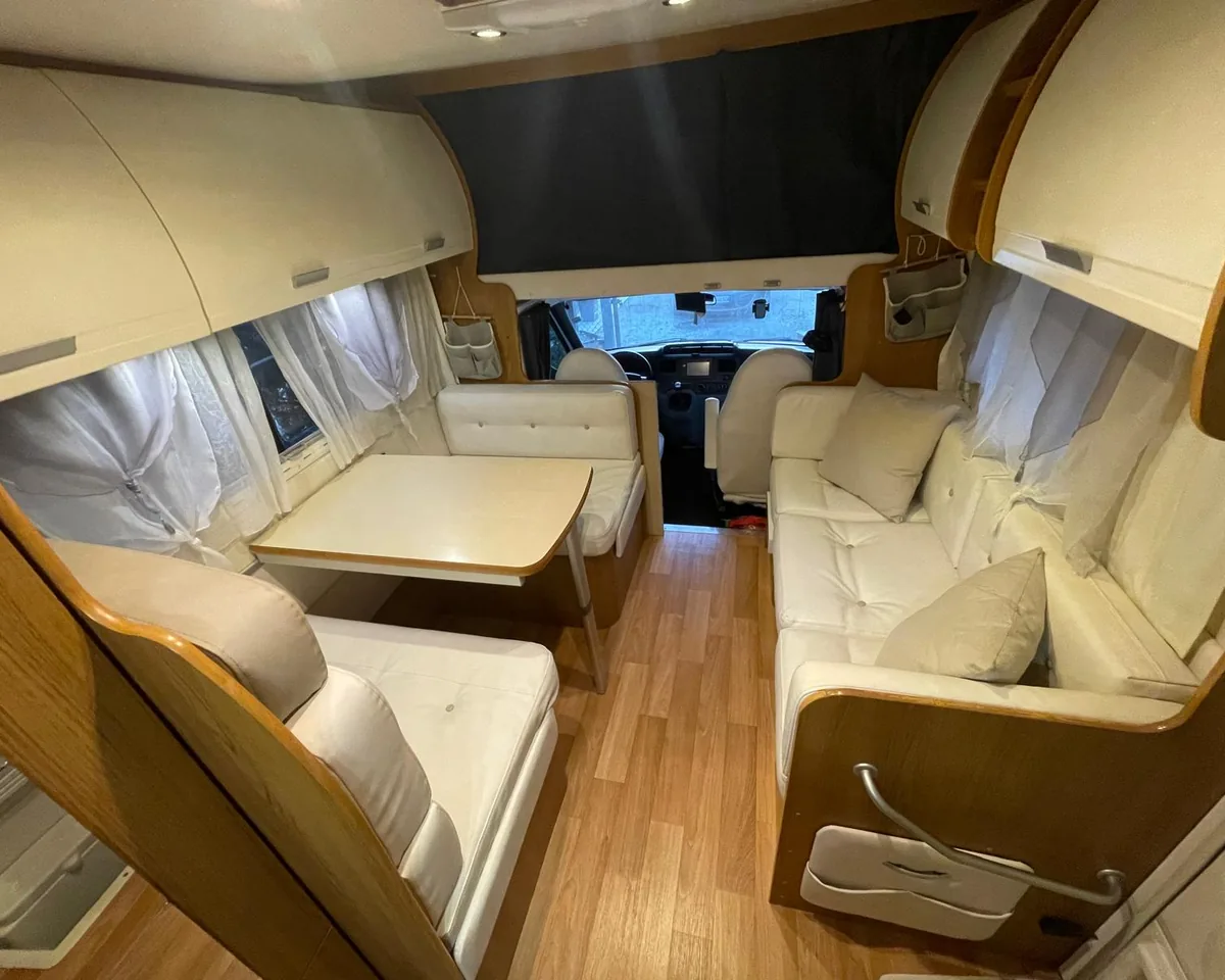 Rivestimenti interni per camper: interno di un camper con dinette e divano laterale rifatti in finta pelle bianca capitonné