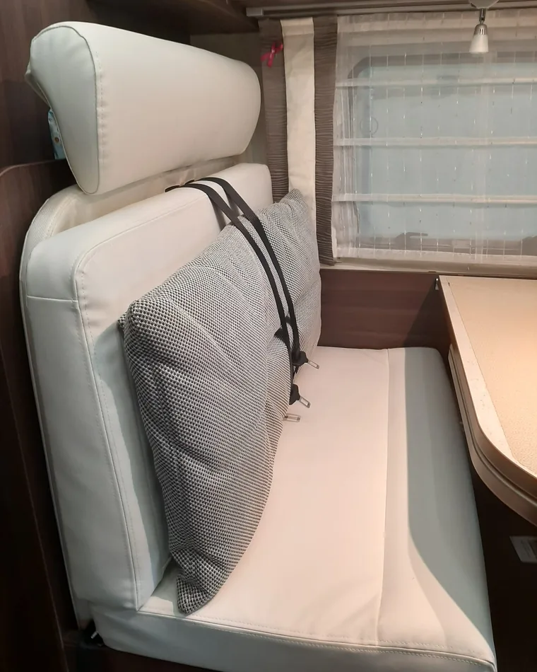 Rivestimenti dinette camper: panca della dinette in finta pelle bianca liscia con poggiatesta e cuscino in tessuto grigio