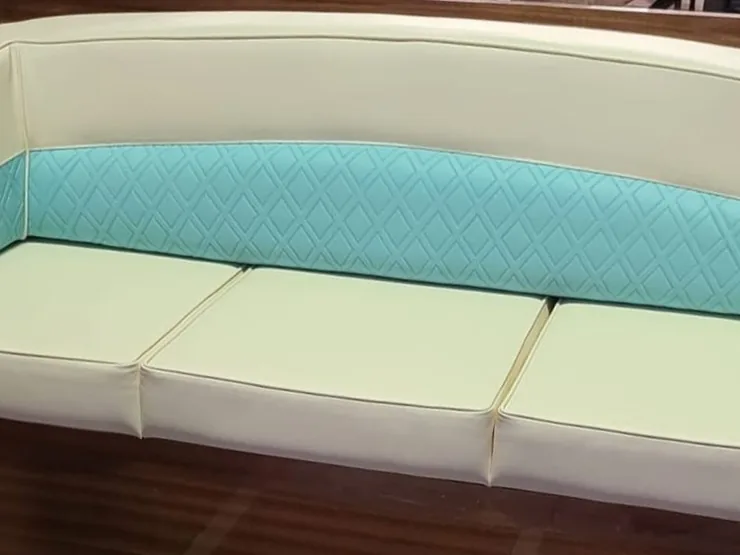 Rivestimenti per barche: divano di un motoscafo taxi in similpelle avorio con fascia trapuntata color acqua, sagomato sullo scafo