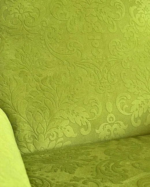Restauro di poltrone: primo piano del tessuto damascato verde acido su seduta e bracciolo