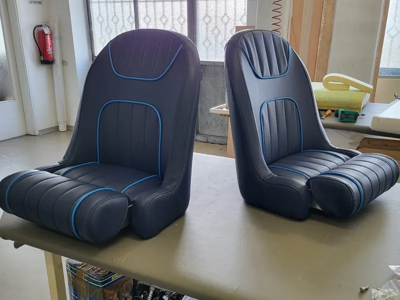 Riempimenti per cuscini nautici: due sedili sportivi in similpelle blu con bordino azzurro, appena finiti in laboratorio