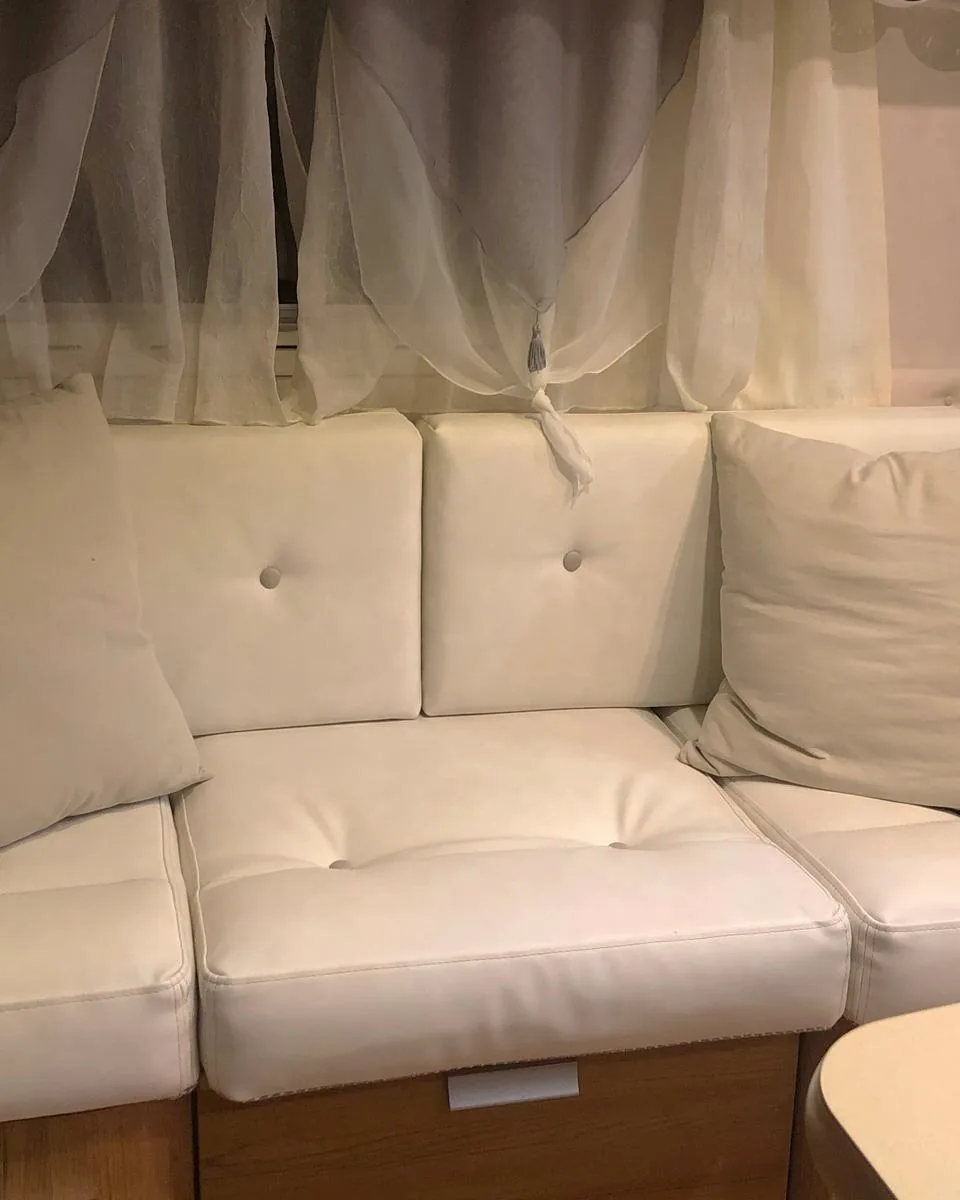 Tappezzeria su misura per camper: divanetto angolare della dinette in finta pelle bianca con bottoni e cuscini in tessuto beige